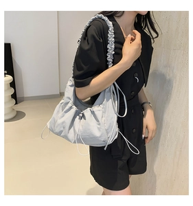 Detail of grey ruffled nylon shoulder bag showing pleated texture and wide strap