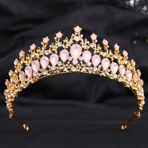 Detail of golden alloy crown with pink teardrop gemstones and white crystals on black fabric