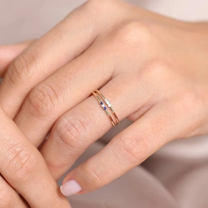 Close-up of two thin gold 925 silver rings with blue and white diamond stones