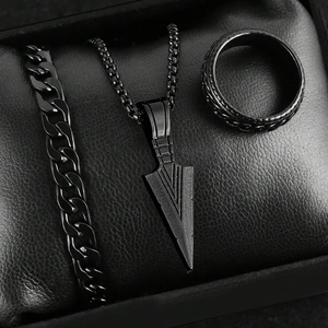 Macro shot of 3-piece matte black men's jewelry set featuring chain bracelet, ring and arrow pendant