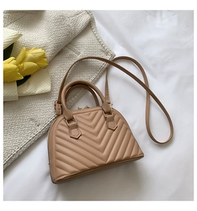 Detail of chevron quilted shell handbag in beige featuring gold zippers and round handles