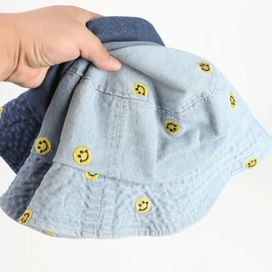 Detail of blue denim bucket hats with yellow smiley face embroidery and stitching
