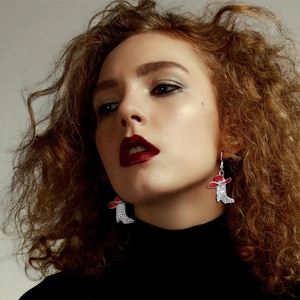 Close-up of sparkling western cowboy boot and red hat earrings worn by a model