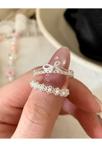Detail of silver bow and lace flower rings with pearl inlay on finger