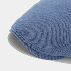 Detail of high-density knitted Morandi blue newsboy hat texture and stiff curved brim