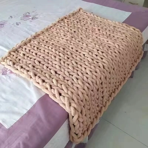 Handmade chunky knit pink chenille blanket with thick textured weave on a bed
