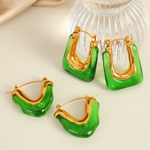 Chic U-shaped gold earrings with emerald green resin on a silk background