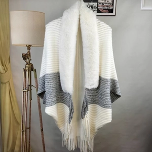 Macro shot of tricolor striped knit shawl featuring a thick faux fur collar and fringe trim