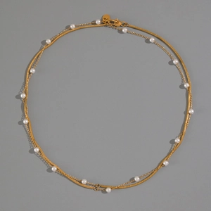 Detail of a vintage double-layer necklace with gold-plated snake chain and white pearls