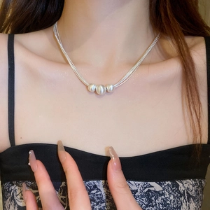 Detail einer eleganten silbernen Mehrschichtkette mit drei gebürsteten runden Perlen am Hals