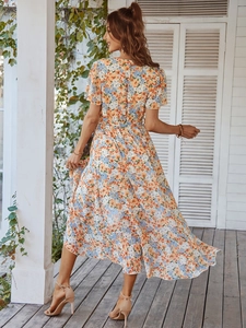 Vue de dos d'une robe longue fleurie trapèze avec imprimé orange et bleu sur une terrasse