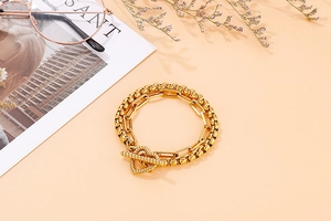 Dettaglio del bracciale a catena a doppio strato dorato con una chiusura a barra a T