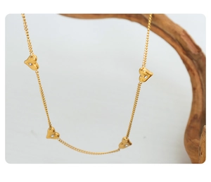 Golden heart necklace with zircons hanging on a wooden branch detail view