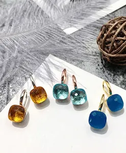 Macro shot of colorful square-cut faceted crystal earrings in blue and amber tones
