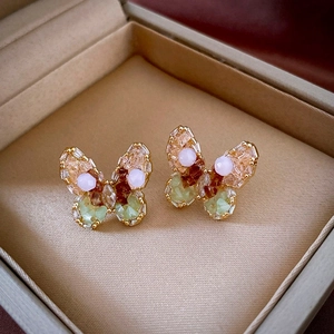 Golden butterfly stud earrings with colorful stones in a beige jewelry box