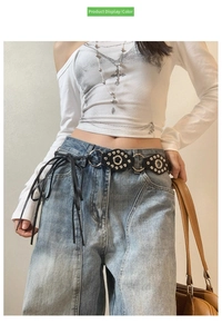 Detail of black leather belt with silver eyelets and rivets on light wash jeans