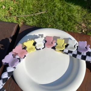 Détail des pinces à cheveux colorées en forme de chat sur un ruban en damier