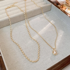Detail of gold-plated pearl pendant and beaded chain necklace in a jewelry box