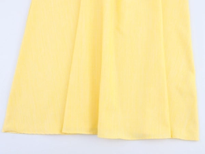 Close-up of yellow floral dress hem with delicate vertical texture and draped fabric