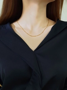 Close-up of a minimalist 18k gold plated stainless steel bead chain necklace on a model