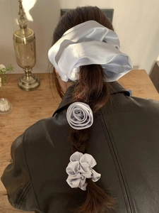 Three-piece satin floral scrunchie set in light blue worn on a braided hairstyle
