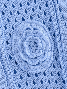 Macro detail of light blue knitted dress showing 3D crochet flower and hollow diamond patterns