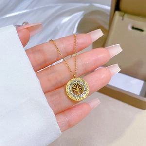 Detail of a gold tree of life pendant featuring hollow design and sparkling crystals