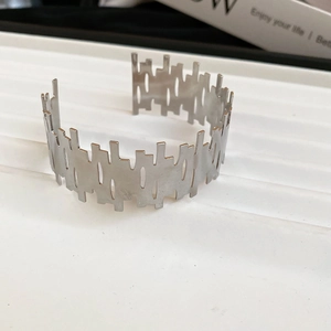 Detailed macro view of irregular silver metal cuff with geometric hollow cut-outs