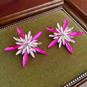 Macro shot of luxury rose red and crystal floral earrings on vintage green velvet