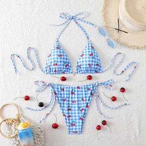 Detailed flat lay of a cherry print bikini set with stylish beach vacation accessories
