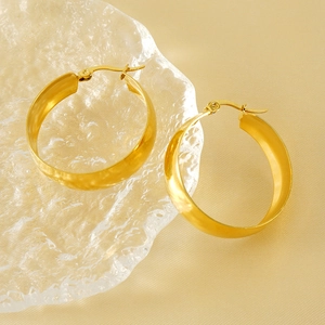 Créoles classiques en acier inoxydable plaqué or 18 carats sur un plateau en verre