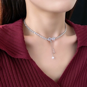 Close-up of zircon bowknot necklace with pearl tassels on a model for a stylish look