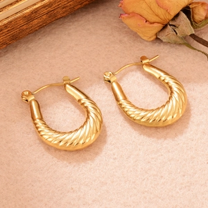 Vue macro de boucles d'oreilles dorées en forme de U avec finition torsadée texturée