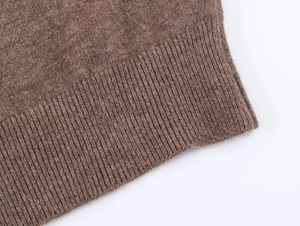 Détail du poignet en tricot côtelé marron foncé et texture en laine de qualité