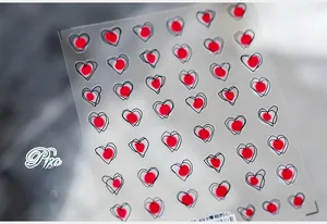 Close-up of 5D heart pattern nail stickers with red dots and black line art on thin film