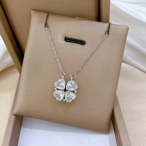 Silver four-leaf clover pendant necklace with heart-shaped crystals in a gold jewelry box