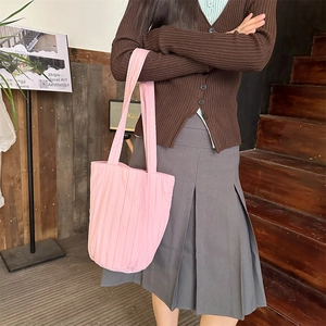 Roze geplooide draagtas met verticale textuur, gestyled met een casual gebreide najaarsoutfit