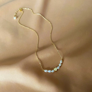 Elegant gold-plated freshwater pearl necklace with heart pendant on champagne silk fabric