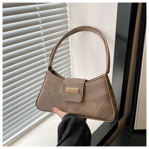 Detailed shot of brown suede underarm bag featuring a gold rectangular metal buckle