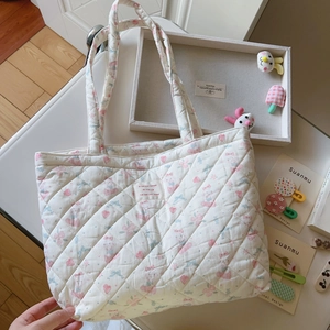 Nahaufnahme der gesteppten Baumwolltasche mit Blumen-Bär-Print und rosa Etikett
