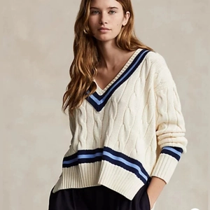 Detail of V-neckline and cable-knit texture on beige oversized striped sweater