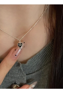 Detail shot of a s925 silver necklace with black heart pendant and bowknot design