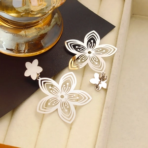 Macro shot of silver hollow cherry blossom earrings on a dark card and velvet jewelry box