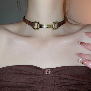 Macro detail of brown leather choker featuring golden brand plaque and Gancini buckles