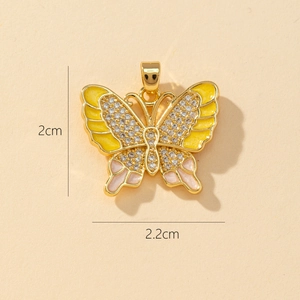 Detail view of a 2cm gold butterfly pendant with colorful enamel and inlaid crystals