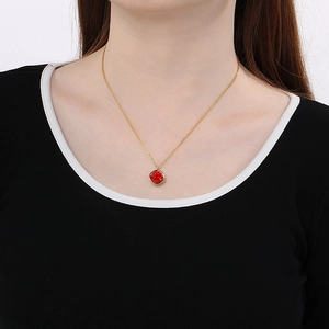 Detail shot of a square red pendant necklace with 18k gold chain on a female model