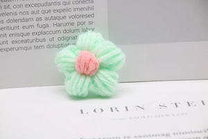 Macro detail of hand-knitted light green milk cotton flower with a soft pink center
