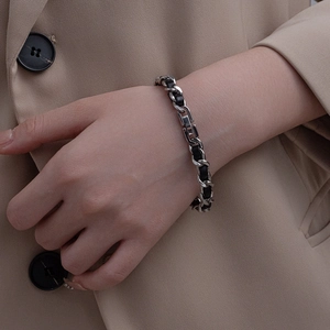 Minimalist silver woven chain bracelet with black leather strips in a retro chic design