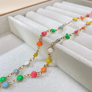 Macro de pendentifs cœurs en émail coloré sur une chaîne dorée dans un coffret bijoux