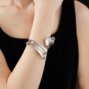 Close-up of a chunky irregular silver twisted metal open cuff bracelet on a model's wrist